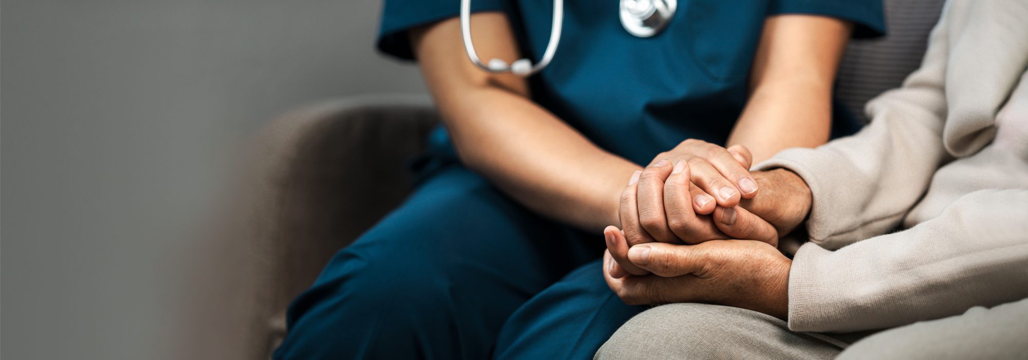 A female nurse caregiver holds hands to encourage and comfort an elderly woman. For care and trust in nursing homes for people of retirement age Caregiver helping elderly woman provides medical advice